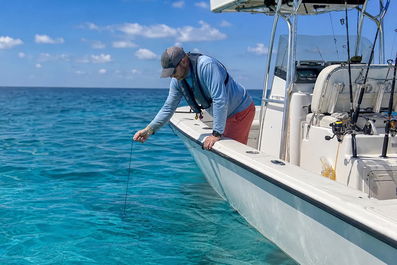 Angler deploying a generic underwater camera cable from a center-console boat in Florida blue water